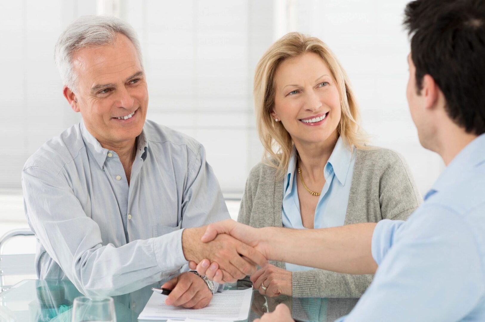 two old couple smiling and shaking a hand